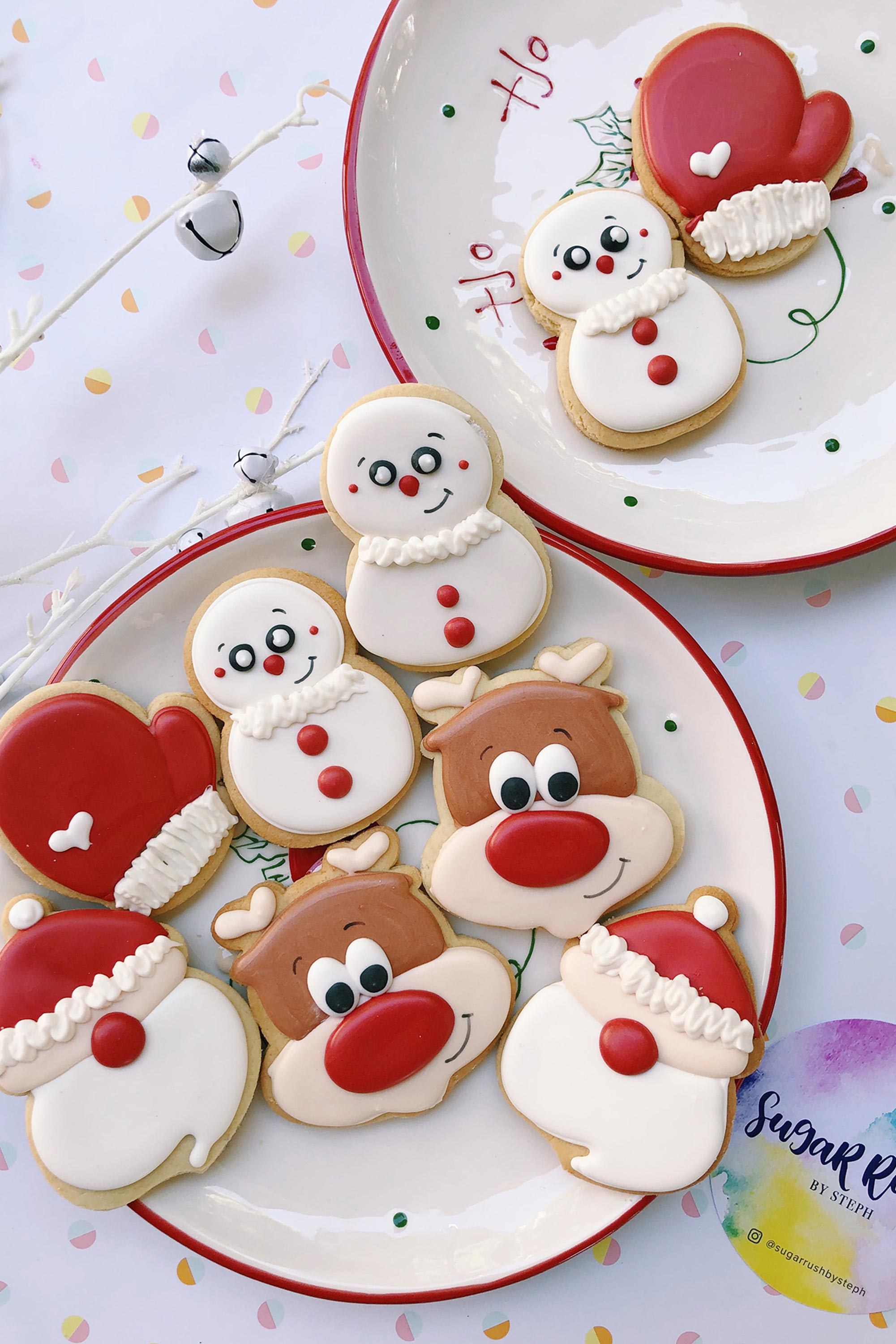 Decorative cookies shaped like Santa Claus, reindeer, and snowmen on a plate with a white background.